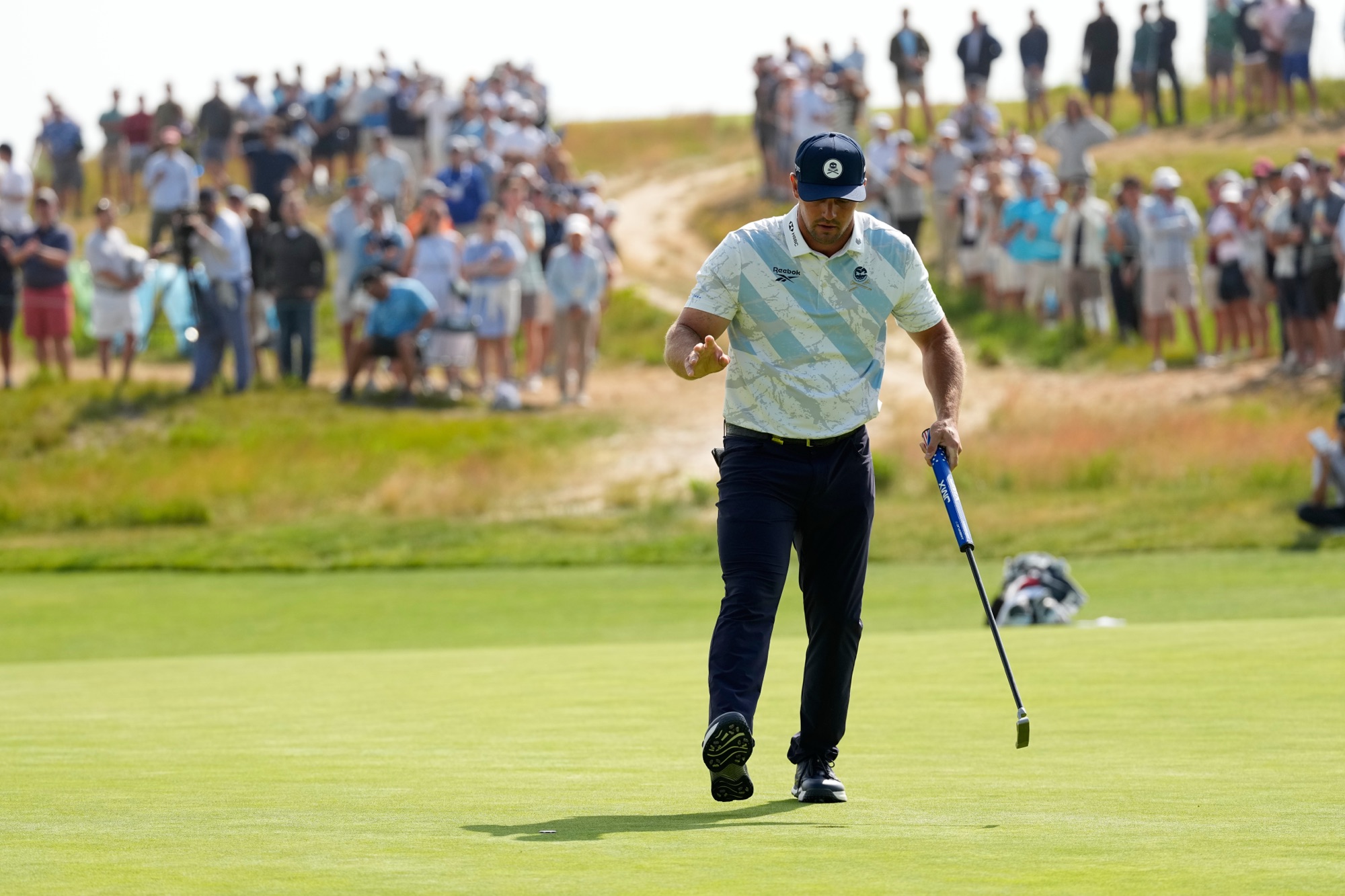 Bryson DeChambeau waves after his putt on the 12th hole during the first round of the U.S. Open golf tournament at Shinnecock Hills Golf Club in Southampton, N.Y., Thursday, June 18, 2026
