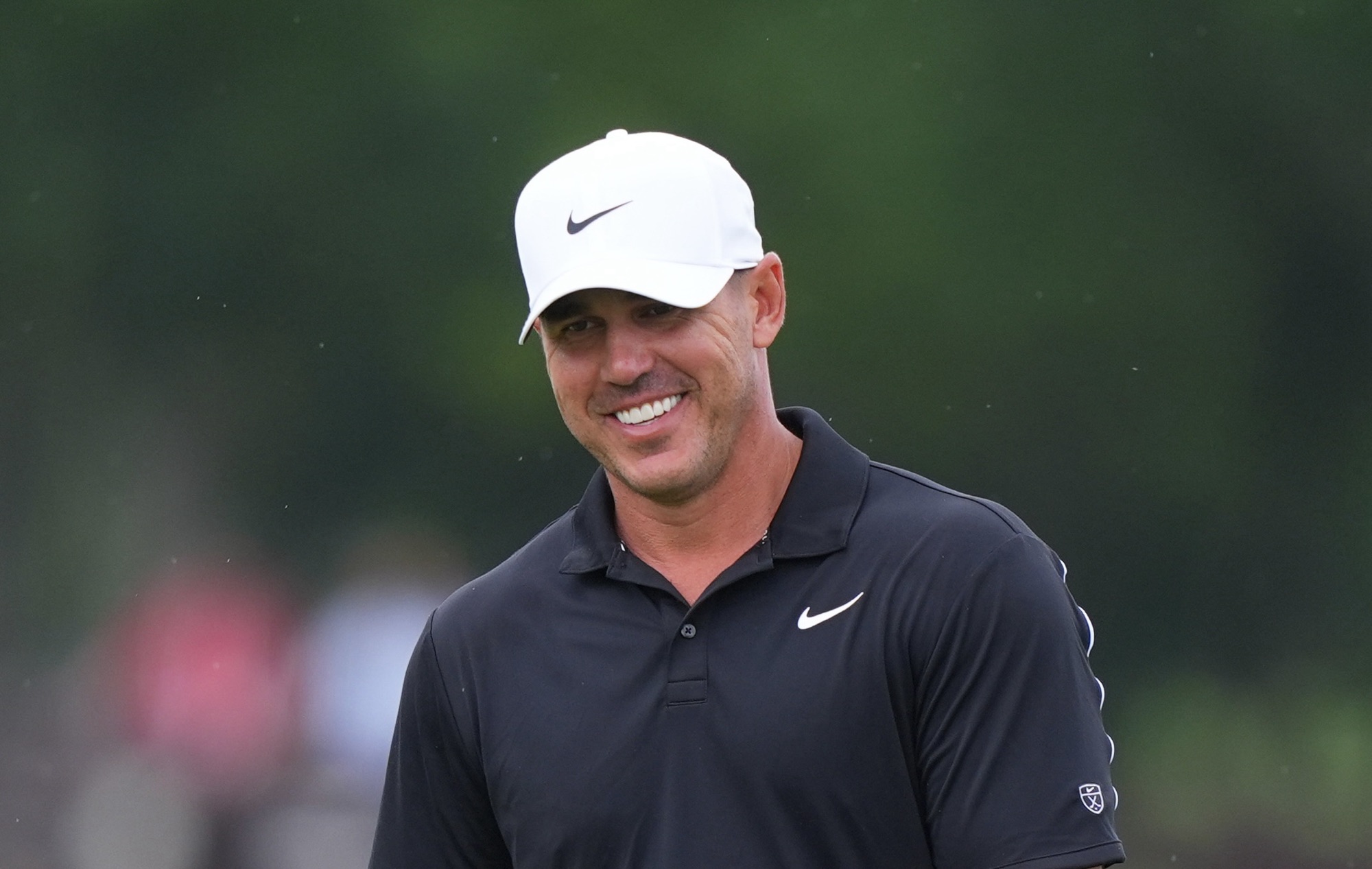 Brooks Koepka smiles while waiting to putt during the 2026 Byron Nelson golf tournament