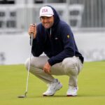 Scottie Scheffler crouches to read a putt on the 14th green during a Presidents Cup practice round at Medinah Country Club