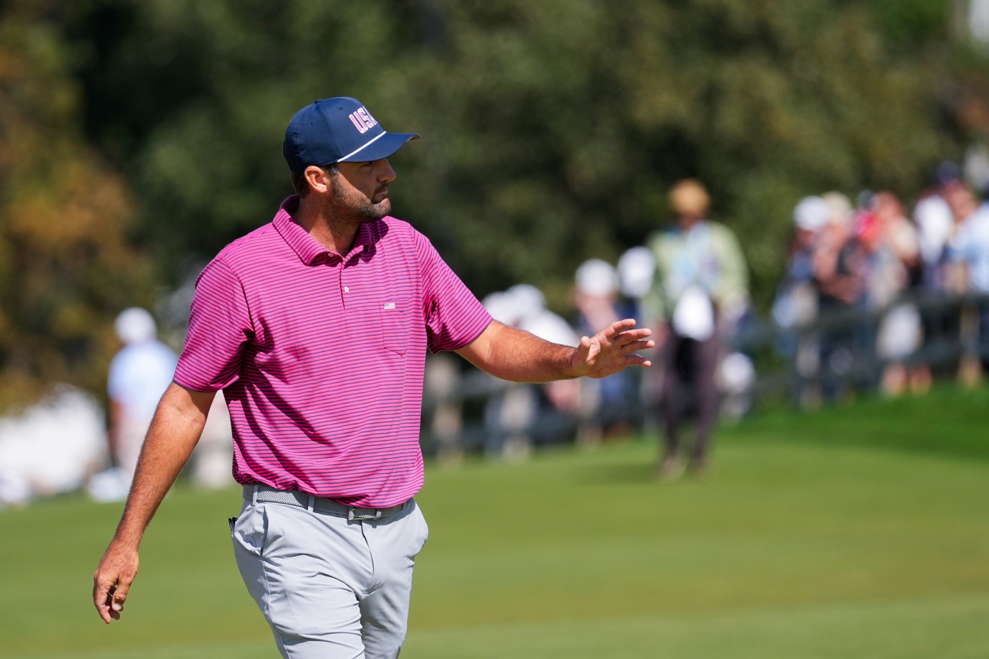 Scottie Scheffler waves on the third green during his Presidents Cup singles match at Medinah Country Club